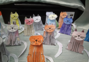 Papierowe koty w różnych kolorach ustawione na stoliku.